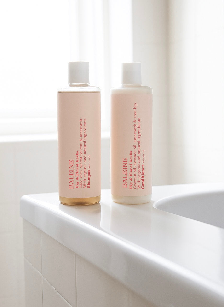 Baleine shampoo and conditioner with grape & neroli on the edge of a bathtub in soft natural light | Baleine shampoo og balsam med grape & neroli på kanten af et badekar i blødt naturligt lys